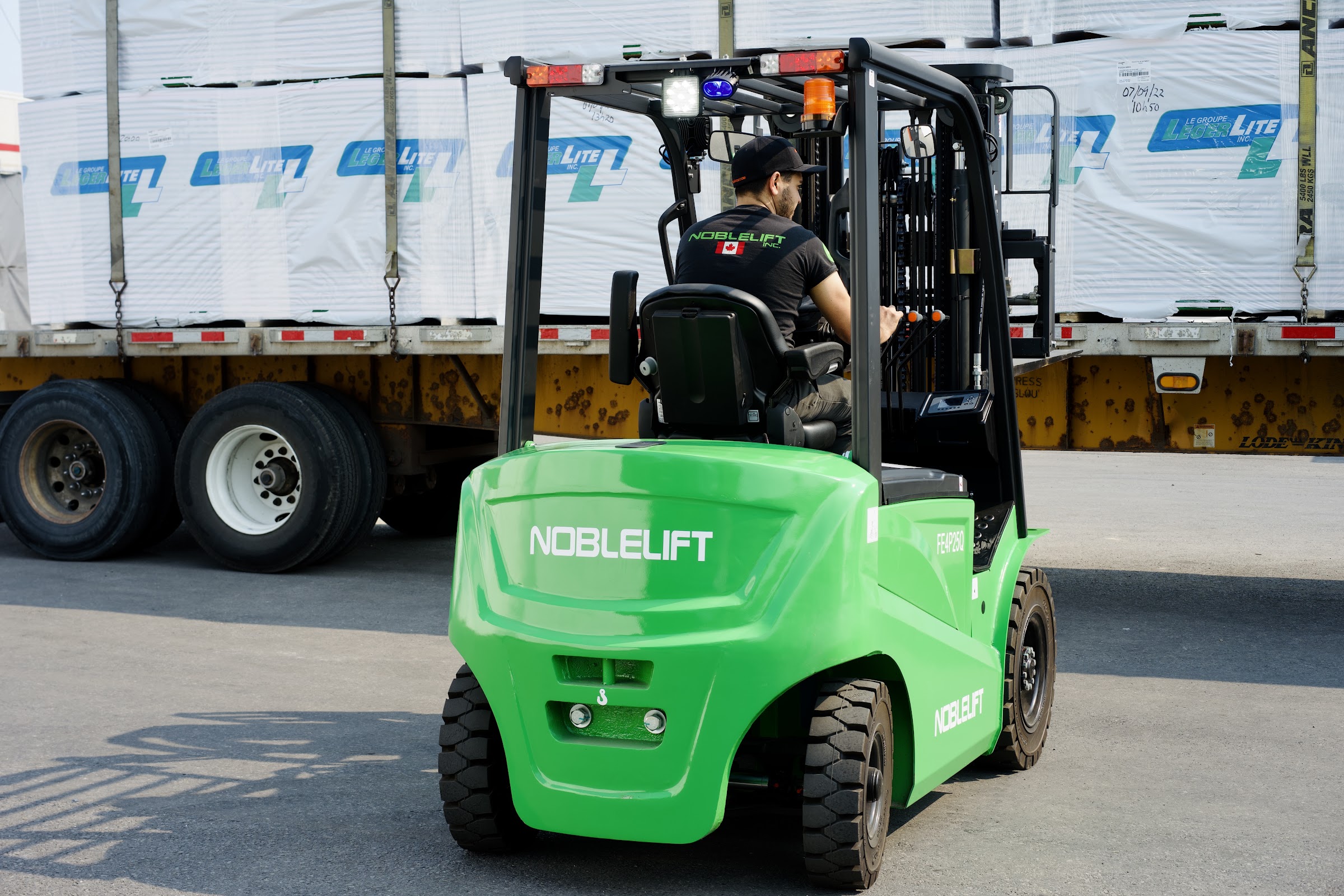Operator driving a Noblelift sit-down counterbalance forklift at a trailer