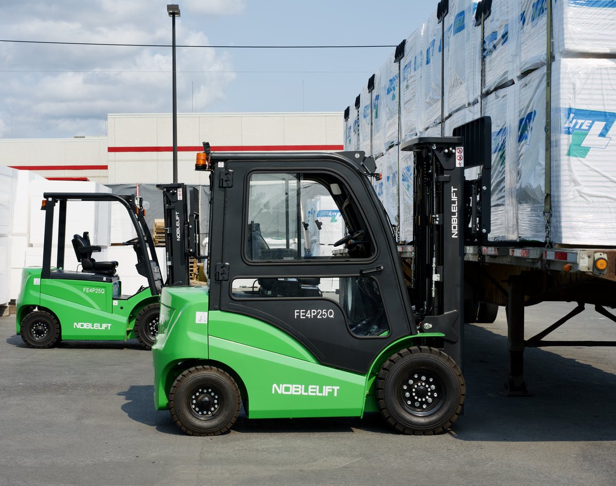 Noblelift FE4P25Q electric counterbalance forklift with an enclosed cab beside a loaded flatbed trailer